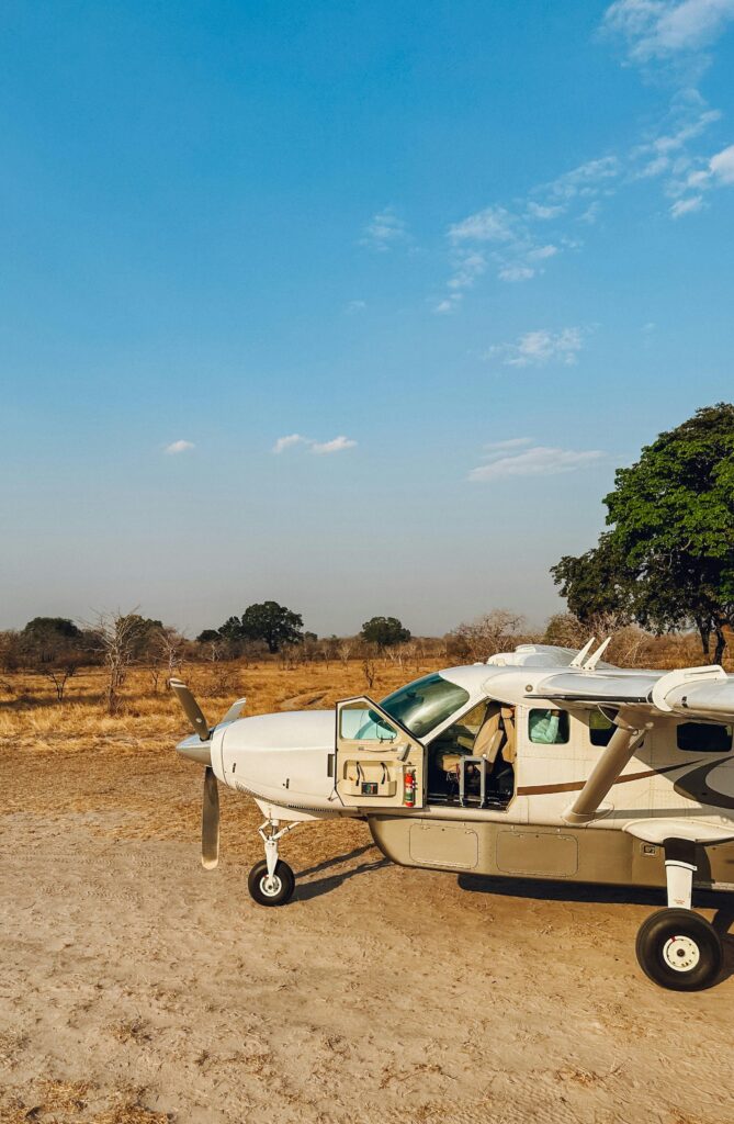 Light aircraft parked on a dry savannah landscape under clear skies.